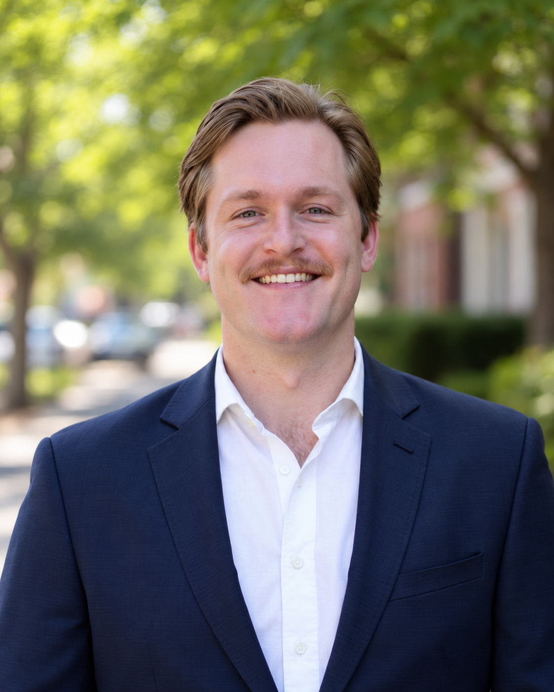 Parker Cox smiling, wearing a navy blazer and white shirt